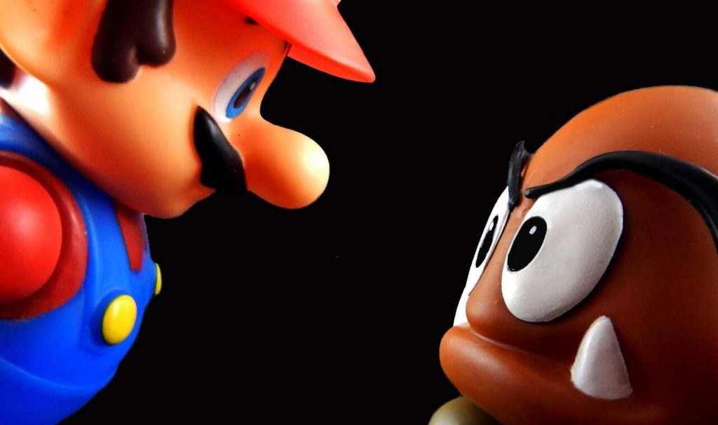 Super-Mario-Figur, die über einen Goomba, ein feindliches Hindernis, springt